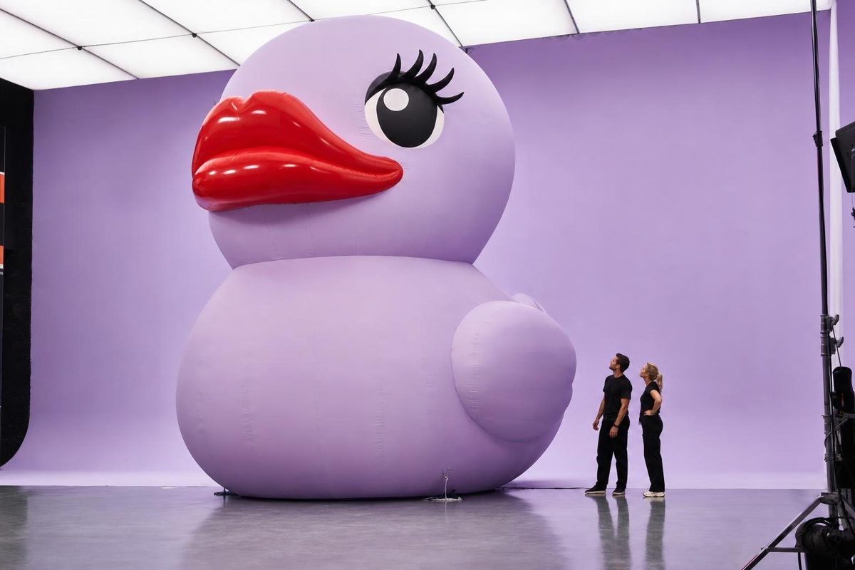 The giant lavender duck character with glossy red lips in a photo studio